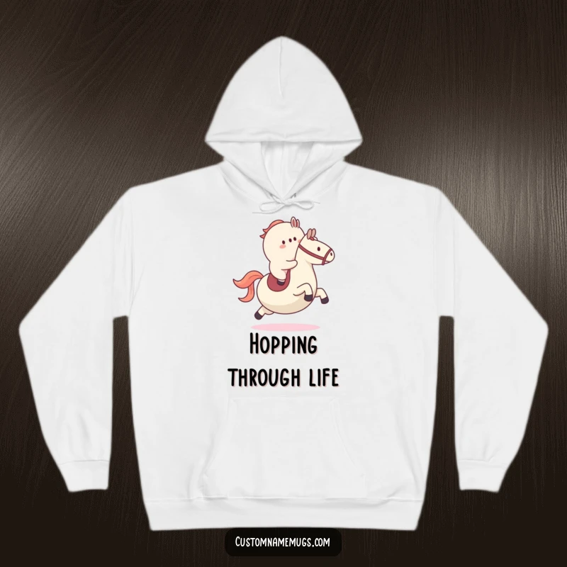 Funny hoodie featuring a determined blob character riding a large bouncy ball like a horse, perfect for cozy, playful moments.