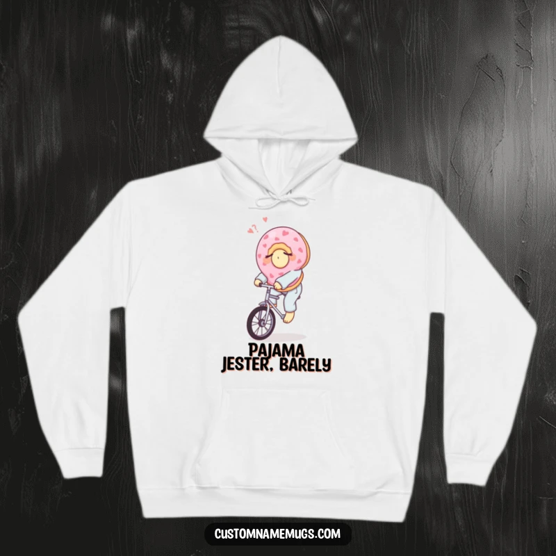 Funny hoodie with a sleepy donut in pajamas riding a unicycle, offering comfort and a humorous, cozy vibe.